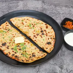 A classic breakfast of Aloo Paratha, served with a dollop of butter, cool curd, and a side of tangy pickle. It's the perfect way to kickstart your morning.