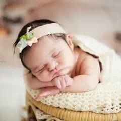 A classic newborn pose, highlighting the delicate features and peaceful sleep of a new baby. The simple headband adds a sweet, gentle touch.