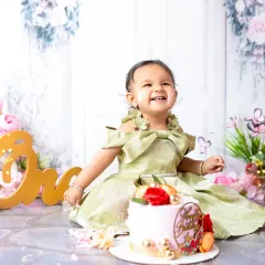 A moment of pure delight during a first birthday cake smash. This little girl's joyful expression is what makes these sessions so special and fun.