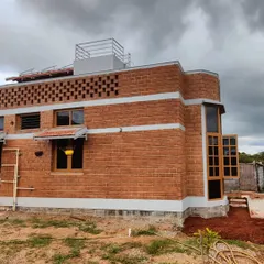 This angle highlights the home's unique curved wall and the intricate brick jaali work on the upper level, which provides ventilation while adding a distinct design element. We ensure every part of the structure is both functional and beautiful.