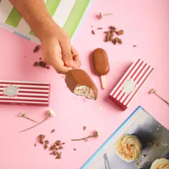 That first bite is always the best. A hand holds our classic chocolate ice cream bar, revealing the creamy vanilla ice cream inside.