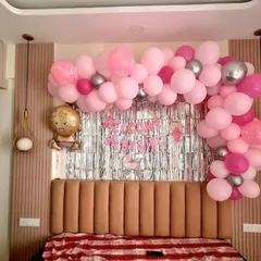 A lovely 'Welcome Baby Girl' decoration for a home. This setup is designed to fit perfectly over a bed, with a pink balloon garland and a silver shimmer curtain.