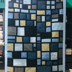 This modern memory quilt was crafted from a collection of denim jeans and T-shirts. We used the different washes of denim and pops of color from the shirts to create a stylish, geometric design.