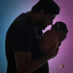 A touching silhouette of a father holding his newborn baby close, showcasing the powerful bond between parent and child. This artistic shot uses dramatic lighting to create a timeless and emotional family portrait.