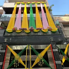 The facade of a modern house decorated with colorful drapes in yellow, pink, and green for a pre-wedding function.