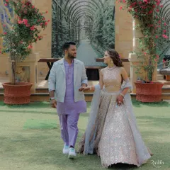 For their Haldi Carnival, we went with a playful and modern pastel theme. I designed a custom tone-on-tone lilac kurta set with a jacquard jacket for the groom, perfectly complementing the bride's bespoke pastel mirror-work lehenga. It was all about fresh colors and fun details, right down to their matching initialed sneakers.