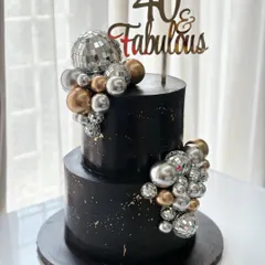 Forty and fabulous! This two-tiered black cake brings the party with shimmering disco balls and a cascade of silver and gold spheres, perfect for a glamorous celebration.