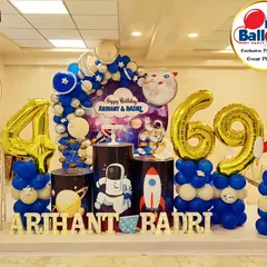 A space-themed party for a 4th and 69th birthday. The decor includes astronaut and rocket cutouts, planet-themed plinths, and large foil number balloons.