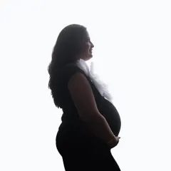 A classic high-key silhouette. The clean white background creates a stark and beautiful outline, focusing completely on the mom-to-be and her baby bump.