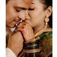 A tender and intimate close-up from an engagement shoot. The focus is on the groom kissing the bride's hand, highlighting her intricate mehndi and traditional green bangles.