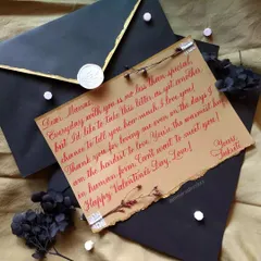 A beautiful note for Valentine's Day, written in a flowing red script on kraft paper. The piece is accented with washi tape, a dried flower, and a custom wax seal on a black envelope.