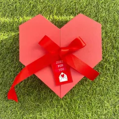 A heart-shaped explosion box for Valentine's Day. This beautifully crafted red box, tied with a satin ribbon, opens up to reveal a collection of sweet surprises inside.