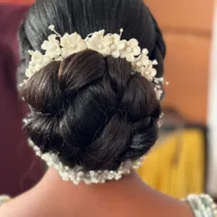This intricate braided bun is a work of art. Adorned with beautiful white floral accessories, it's a stunning choice for a South Indian bride.