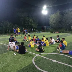 The game isn't just won with your feet, but with your mind. Here, our AIFF licensed coach breaks down tactics with the team under the lights, turning players into thinkers.