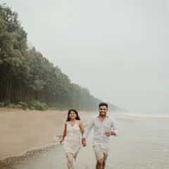 A joyful shot of the couple running hand-in-hand along the shoreline. Their smiles and the natural setting create a feeling of pure, carefree happiness for their beach pre-wedding shoot.