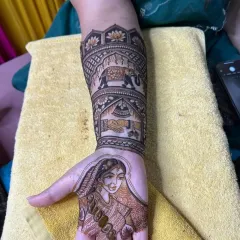 A close-up of a bridal portrait on the palm, surrounded by traditional motifs like the doli and elephant.