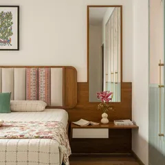 The master bedroom in 'Palaash' embodies a serene garden vibe. The headboard features unique upholstered panels, and the wardrobe is finished in a soft sage green with complementary wallpaper.