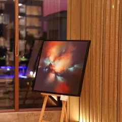 An abstract painting from the 'Mystic Mirage' show, set against the elegant wooden paneling of the JW Marriott. The setting enhances the artwork's dramatic, celestial feel.