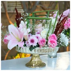 A beautiful floral arrangement in a gold-footed bowl, combining pink lilies, roses, and chrysanthemums for a rich and textured look.