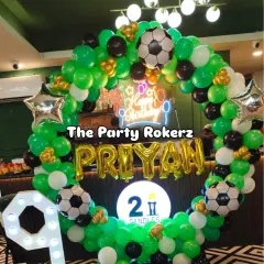 A football-themed birthday party is always a winner. This setup includes a green, black, and white balloon arch, football balloons, a neon sign, and a large light-up number '9'.