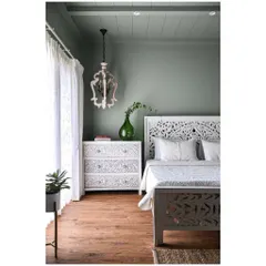 In this master bedroom, we used a soothing sage green on the walls and ceiling to create a cohesive, calming feel. The intricately carved white bed and sideboards add an Indian touch to the tranquil space.