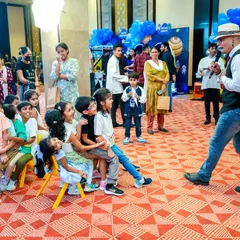 A party host and entertainer engaging a group of seated children with a captivating performance, keeping them entertained and involved.