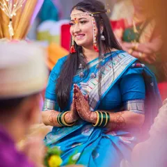 This is a beautiful candid portrait of the bride during a quiet moment in the ceremony. Her respectful gesture and warm smile show her grace and happiness.