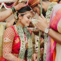 A beautiful moment from a traditional South Indian wedding. I designed this bride's classic red Kanchivaram saree blouse with intricate, heavy embroidery covering the sleeves for a regal muhurtham look.