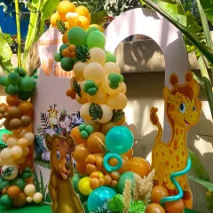 A wild welcome for baby Vamika. This jungle-themed setup features a large balloon arch in earthy greens, oranges, and yellows, complete with cute bear and giraffe cutouts, creating an adorable safari adventure.