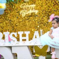 Celebrating a first birthday is a huge milestone. For this outdoor birthday photoshoot, we created a festive setup with a custom name sign, a golden backdrop, and colorful balloons to make it extra special.