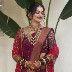 A joyful candid moment of bride Vaibhavi. Her look is enhanced with a red sheer dupatta, layered gold necklaces, and a smile that shows how comfortable and happy she feels.