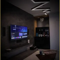 A darker, mood-lit view of the same integrated living room. The automated lighting system allows the ambiance to shift instantly, perfect for transitioning from a social gathering to a movie-watching experience.