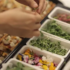 Behind the scenes, our team prepares hors d'oeuvres using fresh herbs and edible flowers, a testament to our commitment to quality.