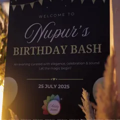 A close-up of the personalized welcome board for "Nupur's Birthday Bash." This custom signage clearly communicates the event details while reinforcing the elegant theme of the evening.