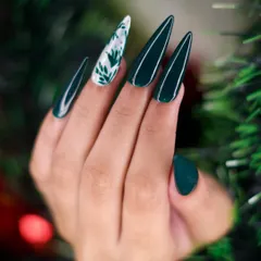 For a more elegant holiday style, I created this set using a deep forest green polish on stiletto nails. The look is elevated with a single white accent nail featuring delicate, hand-painted foliage art.