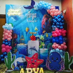 An immersive underwater theme birthday party for a sixth birthday celebration. This detailed setup includes a vibrant ocean backdrop, character cutouts of a shark and octopus, marquee letters, and themed balloon columns.