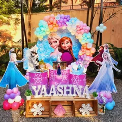 A magical Frozen theme for Yaashna's 6th birthday. This outdoor setup includes a vibrant pastel balloon arch, life-sized cutouts of Elsa and Anna, and custom-themed pedestals for the cake, all designed to transport the kids straight to Arendelle.