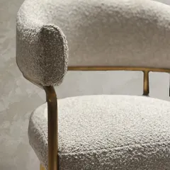 A detail shot of the custom bouclé chair, showing the texture of the fabric and the refined finish of the gold accented frame.