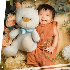A happy three-month-old baby boy cuddling with his teddy bear. These milestone sessions are perfect for capturing their budding personality.