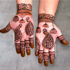 I love creating peacock mehendi. This design showcases twin peacocks on each palm, surrounded by hanging jhumkas, creating a symmetrical and festive look.
