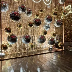 Celebrating 50 years of love with a touch of retro glam. This anniversary setup features a wall of shimmering gold fringe and dozens of silver and gold disco balls, creating a dazzling dance floor for the happy couple.