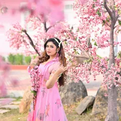 A dreamy, whimsical portrait set in a field of pink cherry blossoms. This is an example of a themed pre-wedding shoot that creates a romantic and fairytale-like atmosphere.