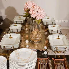 A beautifully curated table setting for a Diwali dinner, featuring marble-patterned plates, gold-accented cutlery, and delicate floral decor.