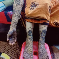 This full bridal package showcases a beautiful contrast between dense patterns on the feet and more spaced-out floral designs on the arms, all done with organic henna.