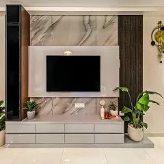 This entertainment wall combines multiple textures for a luxurious look. We used a grey marble-finish laminate as the backdrop, framed by dark fluted panels and a sleek grey console with ample drawer storage for a modern and organized living room.