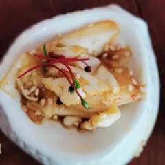 A beautifully composed salad with sesame seeds and micro-amaranth, served in a shell-shaped dish. We pay close attention to texture, flavor, and presentation in every dish.