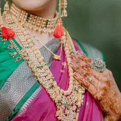 A detail shot focusing on the bride's stunning temple jewellery, intricate mehndi design, and the rich fabric of her saree.