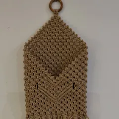 Keep your space organized with this handy macrame pocket wall hanging. It's perfect for storing mail, magazines, or other small items, and the wooden ring makes it easy to hang anywhere.