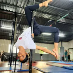 Persistence meets elegance. This student holds a graceful inverted pose, a celebration of the strength and artistry that defines our approach to pole fitness.