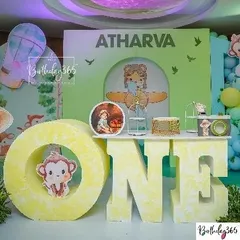A close-up of the "Wild One" jungle theme for Atharva, featuring a large "ONE" sign with a cute monkey, a custom backdrop, and a pilot-themed character.